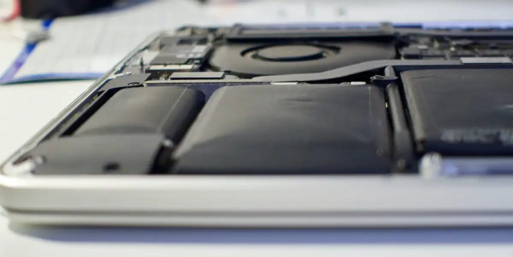 Swollen lithium-ion battery cells bulging inside an opened MacBook Pro